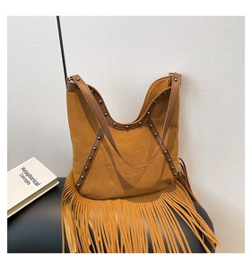 Close-up of brown suede shoulder bag featuring sun embossing, studs, and long fringe