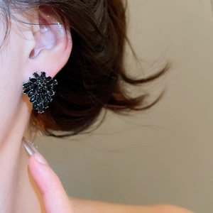 Close-up of elegant black flower stud earrings with marquise crystals on a model's ear