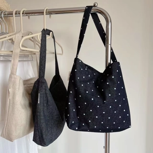 Detail view of canvas tote bags in solid and polka dot patterns with woven labels