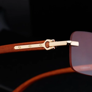 Macro shot of gold C-decor metal hinge and wood grain temple on rimless sunglasses