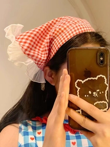 Detail view of red checkered headband with white ruffles worn by a woman in a mirror selfie