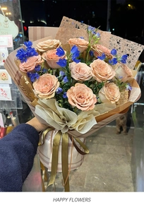 Detail of elegant champagne roses with blue delphinium in brown checkered flower wrapping