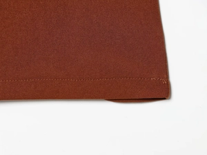 Close-up of brown fabric texture and precise hem stitching on long-sleeve top and pants
