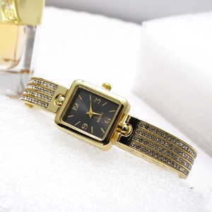 Detail of square gold watch with black dial and crystal-encrusted bangle bracelet
