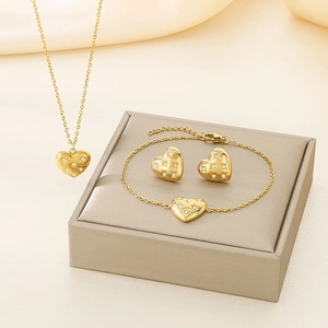 Detailed view of luxury gold heart jewelry set with necklace bracelet and earrings on silk