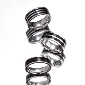 Minimalist titanium steel striped rings in silver and black stacked on a reflective surface