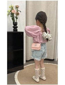 Rear view of pink quilted star crossbody bag paired with puff sleeve top and denim shorts