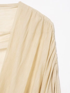 Detail view of the elegant shoulder pleats and soft knitted fabric texture on the beige top