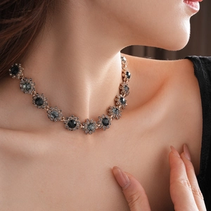 Detailed view of a vintage floral necklace with black stones on a model's neck