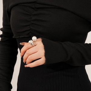 Detail of silver open ring with large white pearl and faceted crystal on a finger