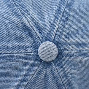 Detailed macro view of the washed denim baseball cap crown showing stitching and top button