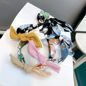 Detail of fabric bow headbands with floral patterns and scalloped edges on a display stand