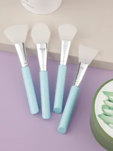Detailed view of four silicone face mask brushes with blue handles on a marble surface