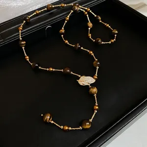 Tiger eye stone long necklace with zircon leaf pendant on a black jewelry box