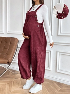 Detail view of burgundy corduroy maternity overalls featuring adjustable side buttons