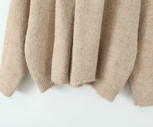 Detailed macro view of the beige knit sweater ribbed hem and soft fabric texture