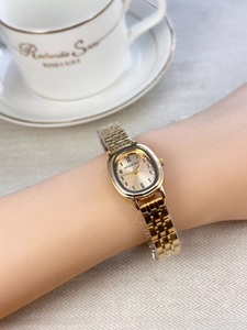 Close-up of elegant gold oval watch with metal chain strap on woman's wrist