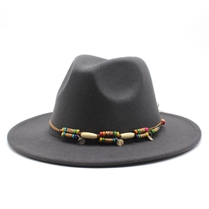 Détail de perles bohèmes et breloques en métal sur un chapeau fedora en laine gris foncé