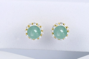 Macro detail of gold stud earrings with light green stone and white diamond halo