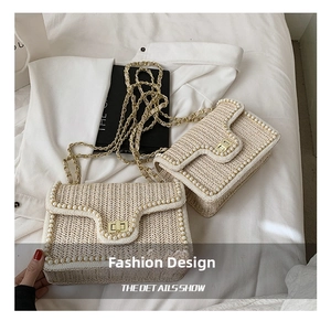Close-up of woven straw shoulder bag with faux pearl trim and golden chain strap