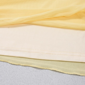 Dettaglio del tessuto in rete gialla con fodera interna beige e cuciture fini sul vestito