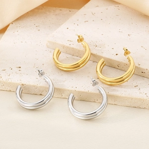 Detailed close-up of gold and silver double-layered C-shaped earrings on stone