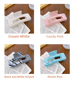 Detail of four square hair claws in marble, stripe, and ripple patterns on a wooden desk