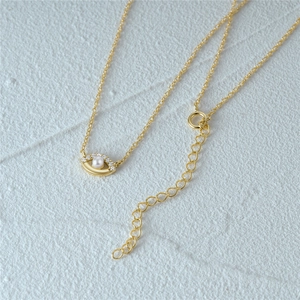 Detail of gold evil eye necklace featuring a central pearl inlay and sparkling zircon accents