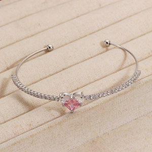 Λεπτομέρεια ροζ ζιργκόν σε σχήμα καρδιάς και διαφανών λίθων σε ασημένιο βραχιόλι
