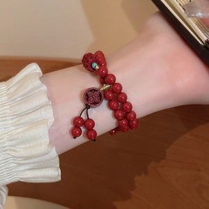 Gros plan d'un bracelet en perles de cinabre rouge avec pendentif sculpté au poignet