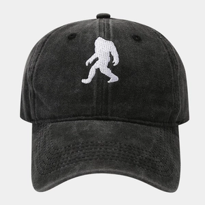 Macro shot of white Bigfoot silhouette embroidery on a black washed cotton baseball cap