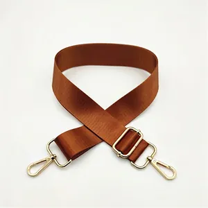 Close-up of brown nylon shoulder strap with golden metal swivel hooks and adjuster