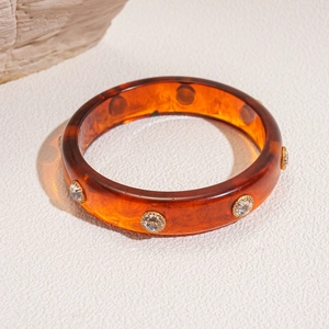 Detail showing amber resin bangle with tortoise pattern and embedded round rhinestones
