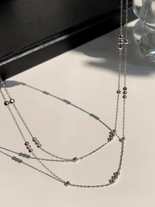 Close-up of double-layer silver beaded necklace made of stainless steel on white surface