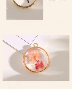 Macro detail of round alloy pendants featuring real dried pink flowers in clear resin