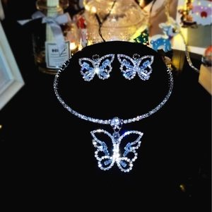 Detail shot of sparkling silver butterfly necklace and earrings on a black stand