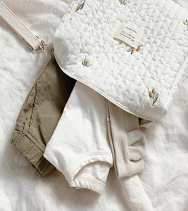 Close-up of olive embroidery on quilted cotton baby diaper bag with stroller straps