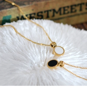 Detail of round shell pendants on gold chains with delicate perlée beaded edges