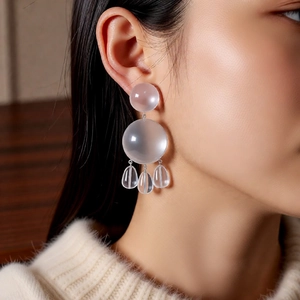 Macro detail of transparent resin triple sphere drop earrings worn by a model