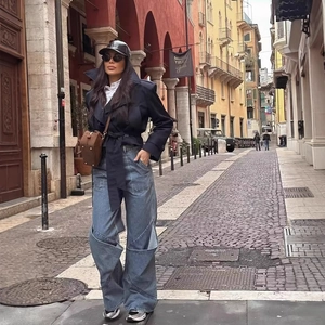 Jean large bleu pour femme assorti à une veste ceinturée dans un décor urbain chic