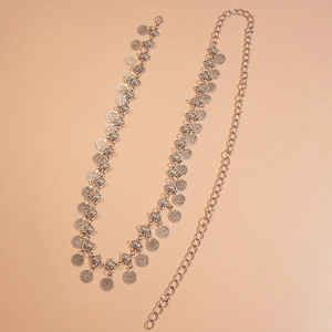 Detail of silver coin waist chain with sunflower connectors on light brown background
