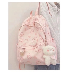 Pink backpack with bear prints and a plush bear pendant shown on a model's back