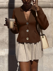 Detail of elegant brown V-neck buttoned knit cardigan vest paired with beige pleated skirt