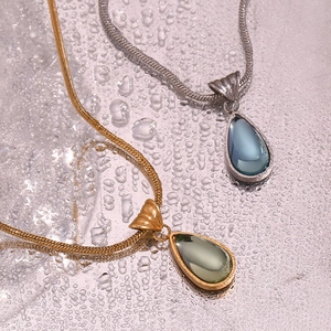 Close-up of teardrop pendants with gemstones on sleek metal snake chains and water drops