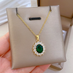 Macro shot of oval emerald pendant with white zircon halo on gold-plated chain