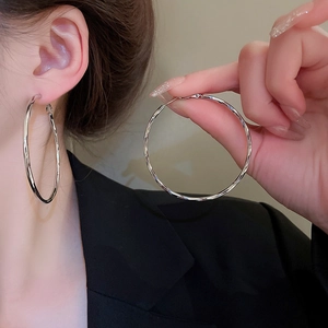 Detail of silver hollow circle earrings with textured surface on ear for a modern style