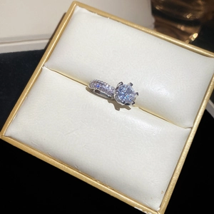 Detailed macro view of a silver six-prong moissanite ring inside a black jewelry box