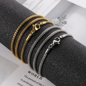 Minimalist gold and silver titanium steel box chains on a textured display stand