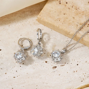 Elegant silver necklace and earrings set with square-cut clear crystals on beige stone