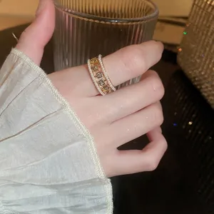 Vintage golden ring featuring pearl edges and square zircon stones on female finger